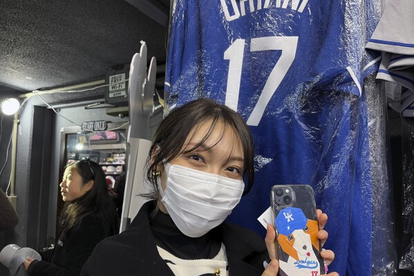 Hina Kishi shows off the Shohei Ohtani design on her smart phone as she shops on Monday Feb 26, 2024, at a sporting goods store, 