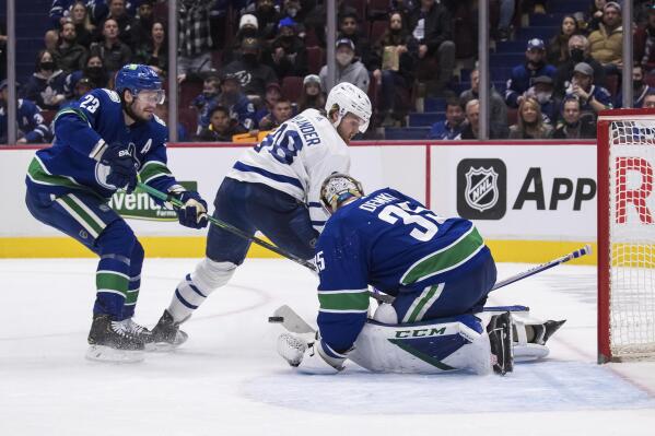 Vancouver Canucks goalie Thatcher Demko (35) stops Toronto Maple Leafs' William Nylander (88) as Canucks' Oliver Ekman-Larsson (23), of Sweden, defends during the third period of an NHL hockey game in Vancouver, British Columbia, Saturday, Feb. 12, 2022. (Darryl Dyck/The Canadian Press via AP)