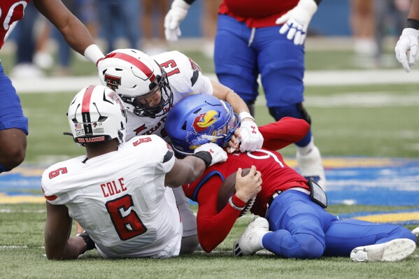 Texas Tech linebackers Ben Roberts (13) and Myles Cole (6) tackle Kansas quarterback Jason Bean (9) during the first half of an NCAA college football game, Saturday, Nov. 11, 2023, in Lawrence, Kan. Bean was injured on the play. (AP Photo/Colin E Braley)