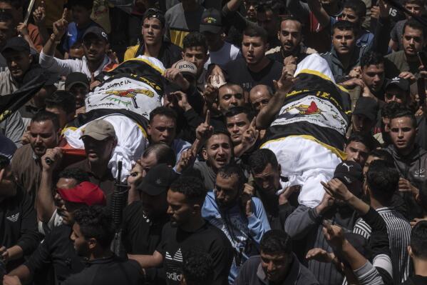 Palestinians carry the bodies of Islamic Jihad commander Ali Ghali, left, and his brother, Mohammed Ghali, both killed in an Israeli airstrike in Khan Younis, southern Gaza Strip, Thursday, May 11, 2023. They are both draped in the Islamic Jihad flag. (AP Photo/Fatima Shbair)