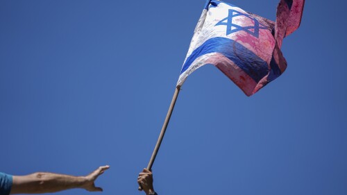 A demonstrator waves a colored Israeli flag during a protest against plans by Prime Minister Benjamin Netanyahu's government to overhaul the judicial system, outside the Knesset, Israel's parliament, in Jerusalem, Monday, July 24, 2023. The demonstration came hours before parliament was set to vote on a key part of the plan. (AP Photo/Ariel Schalit)