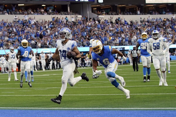 Detroit Lions wide receiver Amon-Ra St. Brown (14) scores a touchdown past Los Angeles Chargers linebacker Eric Kendricks (6) during the second half an NFL football game Sunday, Nov. 12, 2023, in Inglewood, Calif. (AP Photo/Gregory Bull)