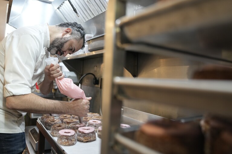 Dominique Ansel ices Cronuts before the opening of his namesake bakery in New York, Thursday, Sept. 28, 2023. In 2013, before most people knew the term “going viral,” the French pastry chef created the Cronut, a cross between a croissant and a doughnut, at his newly opened New York bakery. (AP Photo/Seth Wenig)