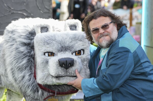 Jack Black poses for photographers with a model wolf character from the film, upon arrival at the World premiere of A Minecraft Movie on Sunday, March 30, 2025, in London. (Photo by Scott A Garfitt/Invision/AP)