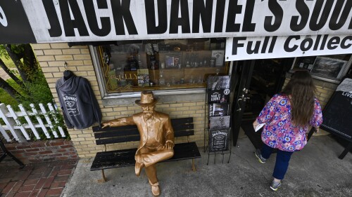 A statue of Jack Daniels sits on a bench as a visitor enters a souvenir shop in the town where the distillery is located Wednesday, June 14, 2023, in Lynchburg, Tenn. A destructive and unsightly black fungus which feeds on ethanol emitted by whiskey barrels has been found growing on property near the distillery's nearby barrelhouses which has resulted in a lawsuit against it. (AP Photo/John Amis)
