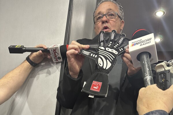 NASCAR Cup Series Managing Director Brad Moran shows reporters, Saturday, March 2, 2024, at Las Vegas Motor Speedway, the illegal glove Joey Logano of Team Penske was caught wearing during qualifying last week at Atlanta Motor Speedway. The webbing between the fingers that give the glove a “Spider-Man” appearance are used to block air when a driver puts his hand out the window during qualifying. (AP Photo/Jenna Fryer)