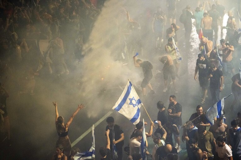 Riot police use water cannon to clear demonstrators with a water canon during a protest against plans by Netanyahu's government to overhaul the judicial system, in Tel Aviv, Monday, July 24, 2023. (AP Photo/Oded Balilty)