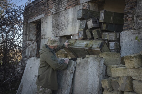 FILE - A sapper examines ammunition left by the Russian troops in the village of Kiseliovka close to Kherson, Ukraine, on Nov. 10, 2023. Two years after Russia’s full-scale invasion captured nearly a quarter of the country, the stakes could not be higher for Kyiv. After a string of victories in the first year of the war, fortunes have turned for the Ukrainian military, which is dug in, outgunned and outnumbered against a more powerful opponent. (AP Photo/Efrem Lukatsky, File)