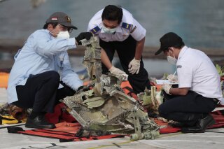 FILE - In this Jan. 21, 2021, file photo, investigators inspect a pieces of the Sriwijaya Air flight SJ-182 retrieved from the Java Sea where the passenger jet crashed on Jan. 9, at Tanjung Priok Port in Jakarta, Indonesia. A lawsuit filed in Seattle against Boeing alleges a malfunctioning autothrottle system on the older 737 jet led to the January crash of the Sriwijaya Air flight that killed all 62 people on board. (AP Photo/Dita Alangkara, File)