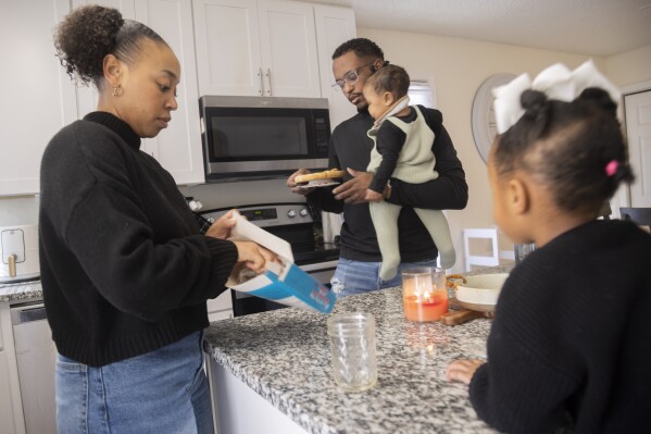 Daizha Rioland, left, and Kenneth Rioland prepare a snack for their daughters, 9-month-old Izabella and Alani, 2, at their home on Saturday, Feb. 17, 2024, in Dallas. The family has struggled to find quality child care for their first daughter. (Juan Figueroa/The Dallas Morning News via AP)