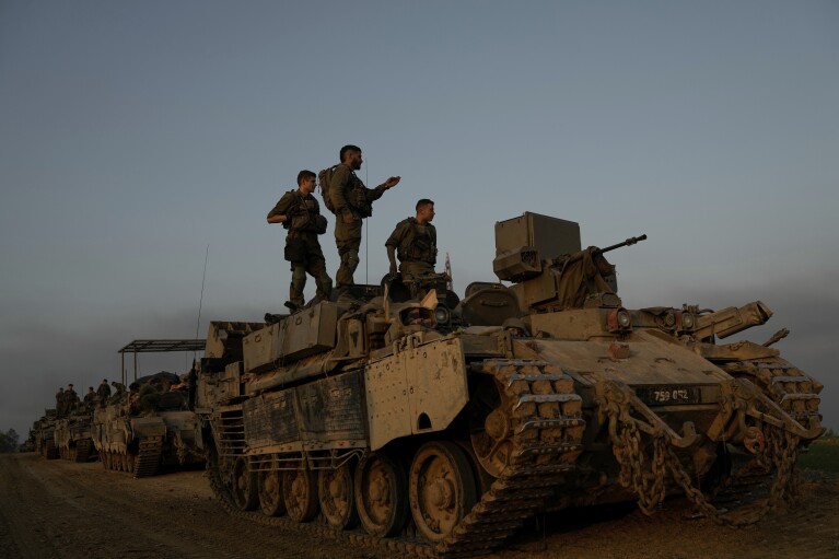 Israeli soldiers stand on top of armoured personnel carriers (APC) near the Israeli-Gaza border, in southern Israel, Monday, Dec. 25, 2023. The army is battling Palestinian militants across Gaza in the war ignited by Hamas' Oct. 7 attack into Israel. (AP Photo/Leo Correa)