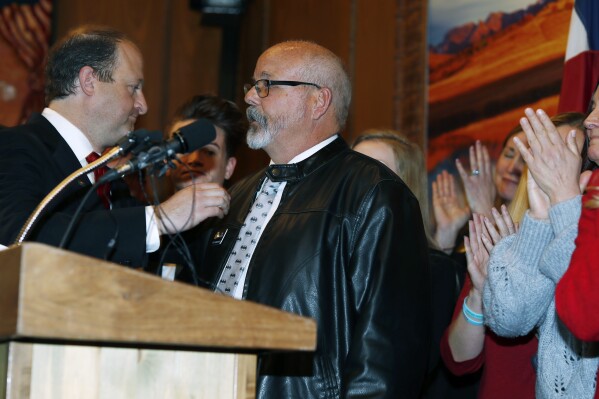 FILE - Colorado Gov. Jared Polis, left, reaches out to Rep. Tom Sullivan, D-Aurora, after his statement about the death of his son in a mass shooting at a movie theatre in Aurora during a bill signing ceremony, April 12, 2019, in the State Capitol in Denver. Colorado’s Democratic-controlled Legislature has nixed a sweeping bill Tuesday, May 7, 2024, to ban the sale and transfer of semi-automatic firearms. (AP Photo/David Zalubowski, File)