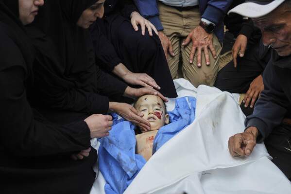 EDS NOTE: GRAPHIC CONTENT - Palestinians mourn over the body of Kinan Edwan, 2 years old, killed in an Israeli army airstrike, during his funeral in Khan Younis, southern Gaza Strip, Saturday, April 19, 2025. (AP Photo/Abdel Kareem Hana)