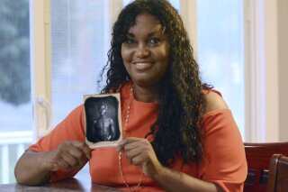 FILE - In this July 17, 2018, photo, Tamara Lanier holds an 1850 photograph at her home in Norwich, Conn., of a South Carolina slave named Renty, who Lanier said is her family's patriarch. The portrait was commissioned by Harvard biologist Louis Agassiz, whose ideas were used to support the enslavement of Africans in the United States. In March 2019, Lanier filed a lawsuit in Massachusetts state court demanding that Harvard turn over the photo and pay damages. In March 2021, a Massachusetts Superior Court judge dismissed the suit. (John Shishmanian/The Norwich Bulletin via AP, File)