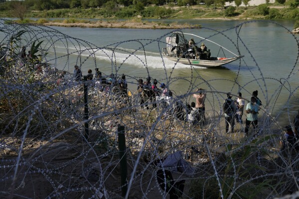 FILE - Migrants who crossed into the U.S. from Mexico are met with concertina wire along the Rio Grande, Sept. 21, 2023, in Eagle Pass, Texas. Texas moved closer Thursday, Oct. 26, to giving police broad new authority to arrest migrants who cross the U.S.-Mexico border, putting Republican Gov. Greg Abbott closer to a new confrontation with the Biden administrations over immigration. (AP Photo/Eric Gay, File)