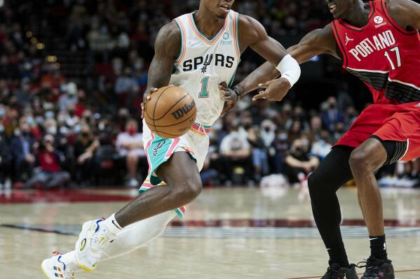 San Antonio Spurs guard Lonnie Walker IV, left, dribbles past Portland Trail Blazers forward Tony Snell during the first half of an NBA basketball game in Portland, Ore., Thursday, Dec. 2, 2021. (AP Photo/Craig Mitchelldyer)