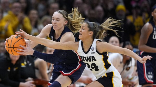 UConn guard Paige Bueckers, left, fights for a loose ball with Iowa guard Gabbie Marshall (24) during the first half of a Final Four college basketball game in the women's NCAA Tournament, Friday, April 5, 2024, in Cleveland. (AP Photo/Carolyn Kaster)