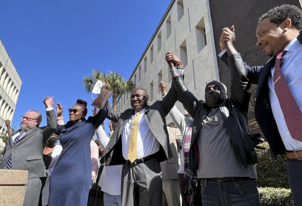 CORRECTS SPELLING OF AHMAUD ARBERY'S LAST NAME - The family and attorneys of Ahmaud Arbery raise their arms in victory outside the federal courthouse in Brunswick, Ga., after all three men involved in his killing were found guilty of hate crimes, Tuesday, Feb. 22, 2022. Greg McMichael, Travis McMichael and William “Roddie” Bryan were found guilty of violating Arbery’s civil rights and targeting him because he was Black. (AP Photo/Lewis M. Levine)