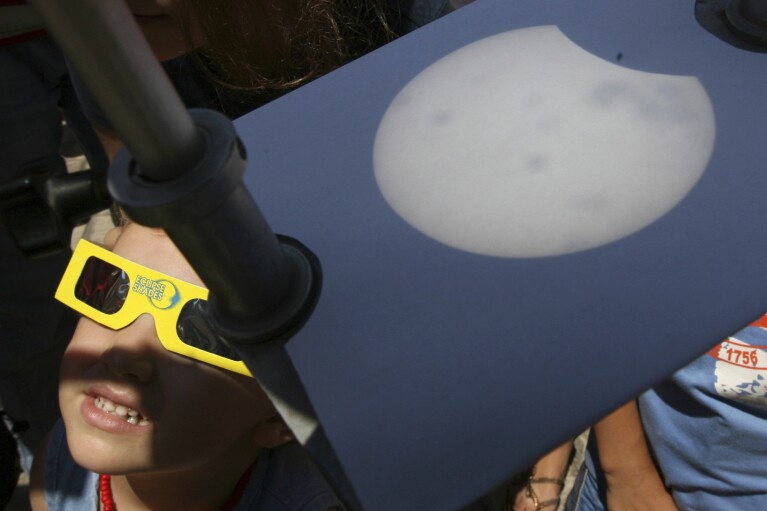 FILE - A child looks through protective glasses at the total eclipse of the sun as a projection of the sun is displayed on card, during a total solar eclipse seen near the Bulgarian's Black sea town of Varna east of the capital Sofia, Friday, Aug. 1, 2008. (AP Photo/Petar Petrov, File)