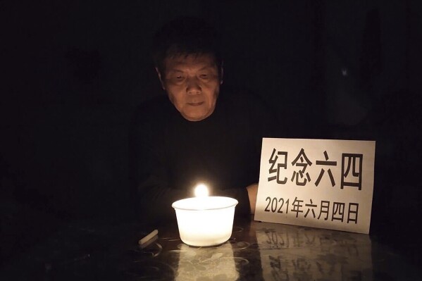 In this photo taken June 4, 2021 and released by Chen Siming, Chen Siming poses for photos with a paper which reads "Commemorate June 4, on 2021, June 4" near a candle light in Zhuzhou in central China's Hunan province. The Chinese dissident known for regularly commemorating the June 4, 1989 crackdown on pro-democracy protesters in Beijing's Tiananmen Square has fled to Taiwan and is pleading for help in seeking asylum in the United States or Canada. (Chen Siming via AP)