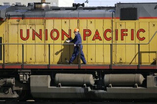 FILE - A maintenance worker walks past the company logo on the side of a locomotive in the Union Pacific Railroad fueling yard in north Denver, Oct. 18, 2006. Union Pacific announced Wednesday, Nov. 1, 2023, that it is trimming the ranks of the railroad's management employees as part of the new CEO's push to eliminate layers of bosses involved in decisions. (AP Photo/David Zalubowski, File)