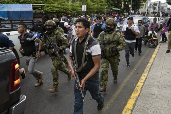 Soldiers and police provide security behind an armored vehicle as supporters of presidential candidate Daniel Noboa, of the National Democratic Action Alliance political party, attend a rally with their candidate in downtown Esmeraldas, Ecuador, Friday, Oct. 6, 2023. Ecuador will hold a presidential runoff, Oct. 15. (AP Photo/Rodrigo Abd)