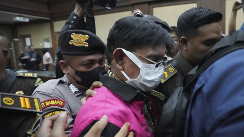 Former Indonesian Communication and Information Minister Johnny G. Plate, center, is escorted by prosecutors and police after his trial at an anti-graft court in Jakarta, Indonesia, Tuesday, June 27, 2023. Indonesia's anti-graft court on Tuesday began a trial for Plate who was charged with corruption over the construction of mobile phone transmission towers in remote parts of the country. (AP Photo/Achmad Ibrahim)