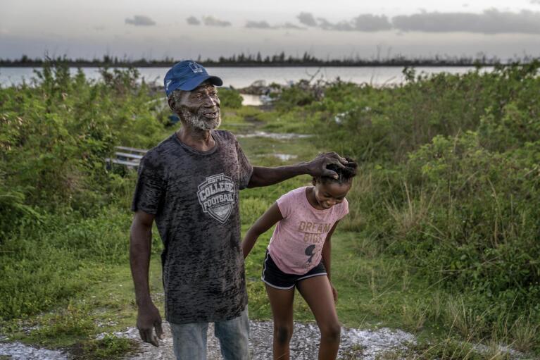 Leroy Glinton, left, a fourth generation conch fisherman, walks with his granddaughter, Savana, 10, outside their home in McLean's Town, Grand Bahama Island, Bahamas, Saturday, Dec. 3, 2022. Savana started diving for conch with her grandfather when she was just eight years old. (AP Photo/David Goldman)