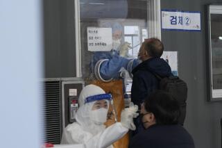 Trabajadores médicos toman muestras nasales de personas en un puesto improvisado de pruebas diagnósticas de coronavirus en Seúl, Corea del Sur, el martes 14 de diciembre de 2021. (AP Foto/Ahn Young-joon)