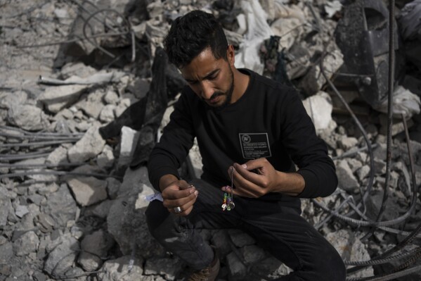 Ibrahim Hassouna, midden, de enige overlevende van zijn familie, zit te midden van het puin van zijn gebombardeerde huis in Rafah, in het zuiden van de Gazastrook, dinsdag 13 februari 2024. Op maandag 12 februari verloor Hassouna acht leden van zijn familie, waaronder drie kinderen en zegt dat het huis werd gebombardeerd tijdens een Israëlische operatie om gijzelaars te redden die werden vastgehouden in een gebouw in een ander deel van de stad.  (AP-foto/Fathima Shabir)
