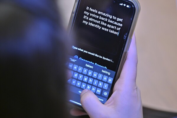 Alexis Bogan types a response to a reporter's question with an app which approximates her lost voice, Thursday, March 11, 2024, at Rhode Island Hospital in Providence, R.I. Doctors treating Bogan, whose speech was impaired by a brain tumor, used a voice-cloning tool from OpenAI to recreate her previous voice. (AP Photo/Josh Reynolds)