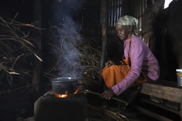 Jane Muthoni, 65, cooks using firewood at her home in Kiambu, Kenya, Tuesday, May 21, 2024. Piles of firewood surrounded Jane Muthoni in her kitchen made of iron sheets. The roof, walls and wooden pillars were covered in soot. As she blew on the flame for tea, the 65-year-old was engulfed in smoke. She was unaware of the lasting toll on her health. (AP Photo/Andrew Kasuku)