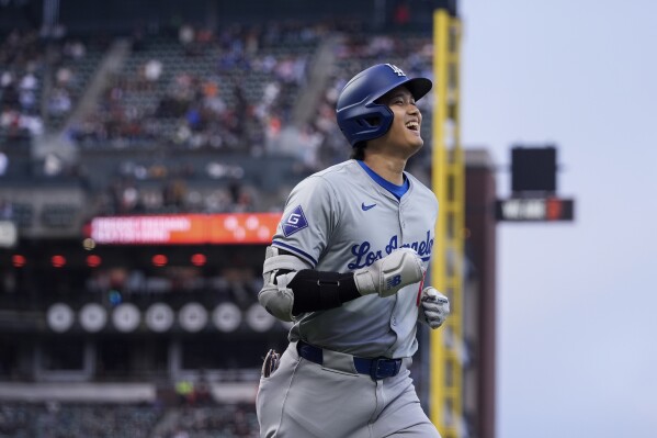 Los Angeles Dodgers' Shohei Ohtani smiles as he jogs to the dugout following his solo home run against the San Francisco Giants during the fourth inning of a baseball game Tuesday, May 14, 2024, in San Francisco. (AP Photo/Godofredo A. Vásquez)