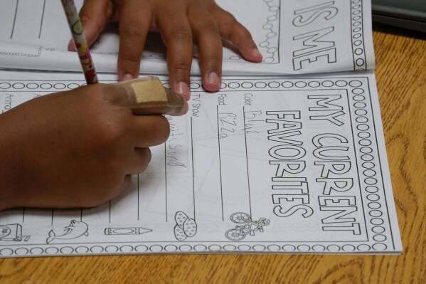 Aaliyah Ibarra works on her memory book during the last week of classes at Frye Elementary School in Chandler, Arizona Tuesday, May 23, 2023. By the time Aaliyah started second grade, her family had moved five times in four years in search of stable housing. As she was about to start a new school, her mother, Bridget Ibarra, saw how much it was affecting her education.(AP Photo/Darryl Webb)