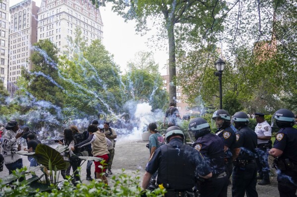 Police officers set off a smoke bomb in order to disperse a crowd, Friday, Aug. 4, 2023, in New York's Union Square. Police in New York City struggled to control a crowd of thousands of people who gathered in Manhattan's Union Square for an Internet personality's videogame console giveaway that got out of hand. (AP Photo/Mary Altaffer)