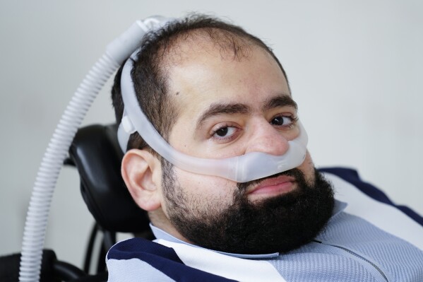 Temple University doctoral student Jaggar DeMarco poses for a photograph while utilizing a battery powered ventilator in Philadelphia, Wednesday, March 6, 2024. DeMarco waited more than three years to get his second ventilator from his health insurer. “Breathing is not a luxury," he said. “It’s really the bare minimum, and that’s what we’re asking for.” (AP Photo/Matt Rourke)