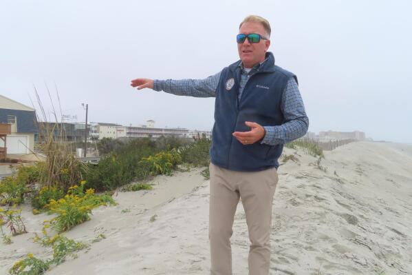 Mayor Patrick Rosenello stands atop a recently repaired dune in North Wildwood, N.J., on Tuesday, Oct. 25, 2022. The town used bulldozers to push sand back into piles to repair severe erosion from recent storms, despite a directive from state environmental officials not to do the work until the proper studies and planning took place. (AP Photo/Wayne Parry)