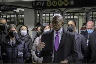 In this livestream frame grab from video provided by NYPD News, Mayor Eric Adams, foreground, with city law officials, speaks at a news conference inside a subway station after a woman was pushed to her death in front of a subway train at the Times Square station, Saturday, Jan. 15, 2022, in New York. (NYPD News via AP)