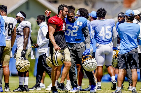 Los Angeles Chargers linebacker Khalil Mack (52) hugs New Orleans Saints quarterback Derek Carr (4) after participating in a joint NFL football practice, Thursday, Aug. 17, 2023, in Costa Mesa, Calif. (AP Photo/Ryan Sun)