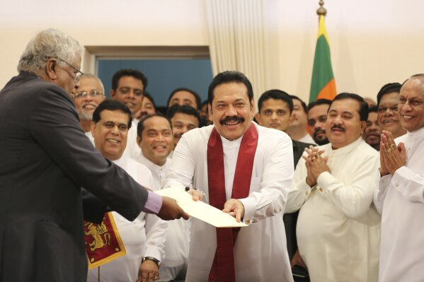 
              Sri Lanka's newly appointed prime minister Mahinda Rajapaksa, center, hands over inaugural documents to an official during his duties assuming ceremony in Colombo, Sri Lanka, Monday, Oct. 29, 2018. (AP Photo/Lahiru Harshana)
            