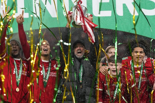 Liverpool's manager Jurgen Klopp lifts the trophy next to Liverpool's Virgil van Dijk as the team celebrates winning the English League Cup final soccer match between Chelsea and Liverpool at Wembley Stadium in London, Sunday, Feb. 25, 2024. (AP Photo/Alastair Grant)