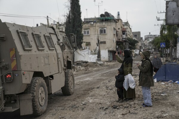 A Palestinian woman flashes a V-sign towards Israeli troops during an army raid in the Tulkarem refugee camp, West Bank, Wednesday, Jan.17, 2024. (AP Photo/Nasser Nasser)