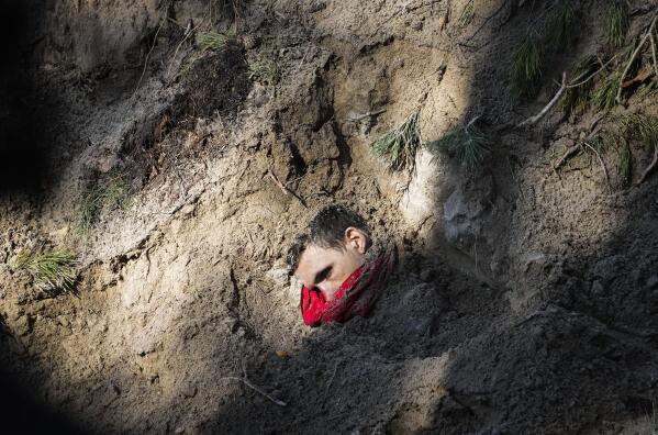 One of four bodies, including the village mayor and her family, is exposed in a mass grave in Motyzhyn close to Kyiv, Ukraine, on April 4, 2022, after Russian forces were pushed from the area by Ukrainians. (AP Photo/Efrem Lukatsky)