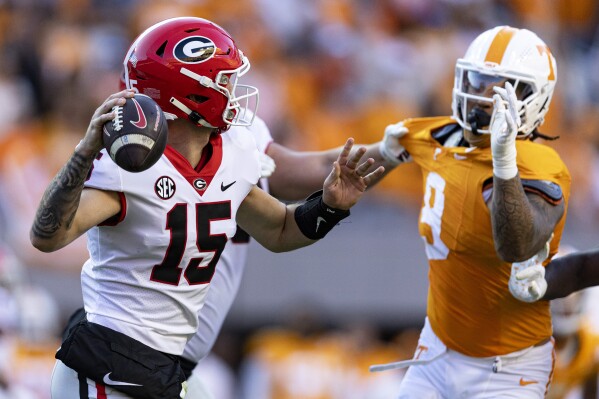 Georgia quarterback Carson Beck (15) throws to a receiver as he's pressured by Tennessee defensive back Brandon Turnage (8) during the first half of an NCAA college football game Saturday, Nov. 18, 2023, in Knoxville, Tenn. (AP Photo/Wade Payne)