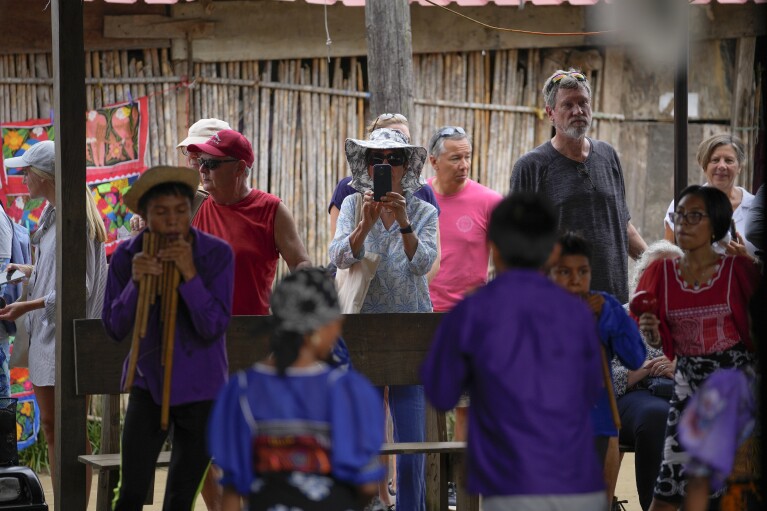 Cruise ship tourists photograph residents of Gardi Sugdub Island, part of the San Blas archipelago off Panama's Caribbean coast, Sunday, May 26, 2024. (AP Photo/Matias Delacroix)