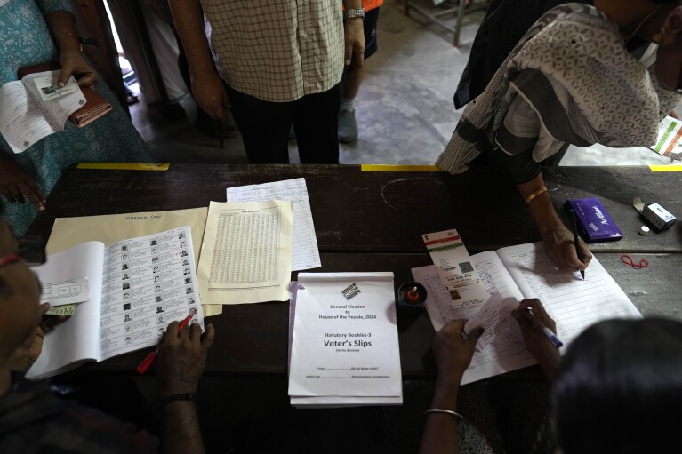 A voter shows her identity papers and signs her name in the polling register before casting her vote during the second round of voting in the six-week-long national election near Palakkad, in Indian southern state of Kerala, Friday, April 26, 2024. (AP Photo/Manish Swarup)