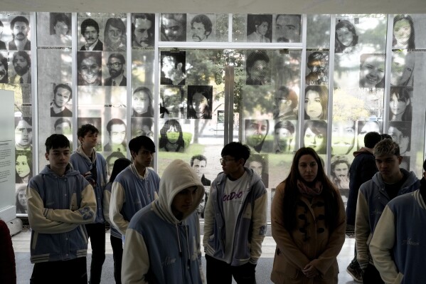 Photographs of people who disappeared during Argentina's dictatorship (1976-1983) are displayed on the wall where students walk through the ESMA Museum and Site of Memory on the day the museum was declared an UNESCO World Heritage Site in Buenos Aires, Argentina, Tuesday, Sept. 19, 2023. The museum was once the Argentine Navy School of Mechanics that was used as an illegal detention and torture center during the Argentina’s last military dictatorship. (AP Photo/Rodrigo Abd)