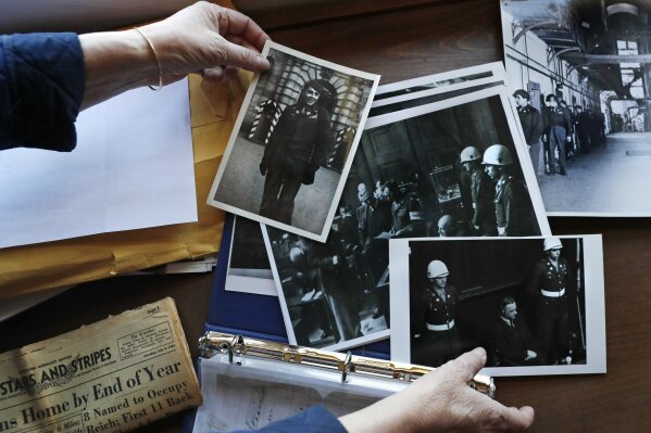 FILE - In this May 13, 2020 file photo, Emily DiPalma Aho looks over photographs and memorabilia of her father, Emilio DiPalma, a World War II veteran, at her home in Jaffrey, N.H. Emilio, who as a 19-year-old U.S. Army infantryman stood guard at the Nuremberg Nazi war crimes trials, died last month at the age of 93 after contracting the coronavirus at Holyoke Soldiers' Home in Massachusetts. The passage of a milestone — 100,000 lives lost due to the coronavirus in the United States — has brought attention to how news organizations are trying to tell the stories behind the numbers. (AP Photo/Charles Krupa, File)