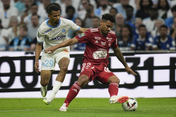 FILE - Brest's Kenny Lala, right, and Marseille's Iliman Ndiaye, left, fight for the ball during the French League One soccer match between Marseille and Brest in Marseille, France, Saturday, Aug. 26, 2023. With one match left to play before the year-end break, the small club from the Brittany region dreams about Europe. After 16 rounds of matches, Brest boasts its best record ever at this stage of any French league season, with eight wins and only four defeats for a total of 28 points. (AP Photo/Daniel Cole, File)
