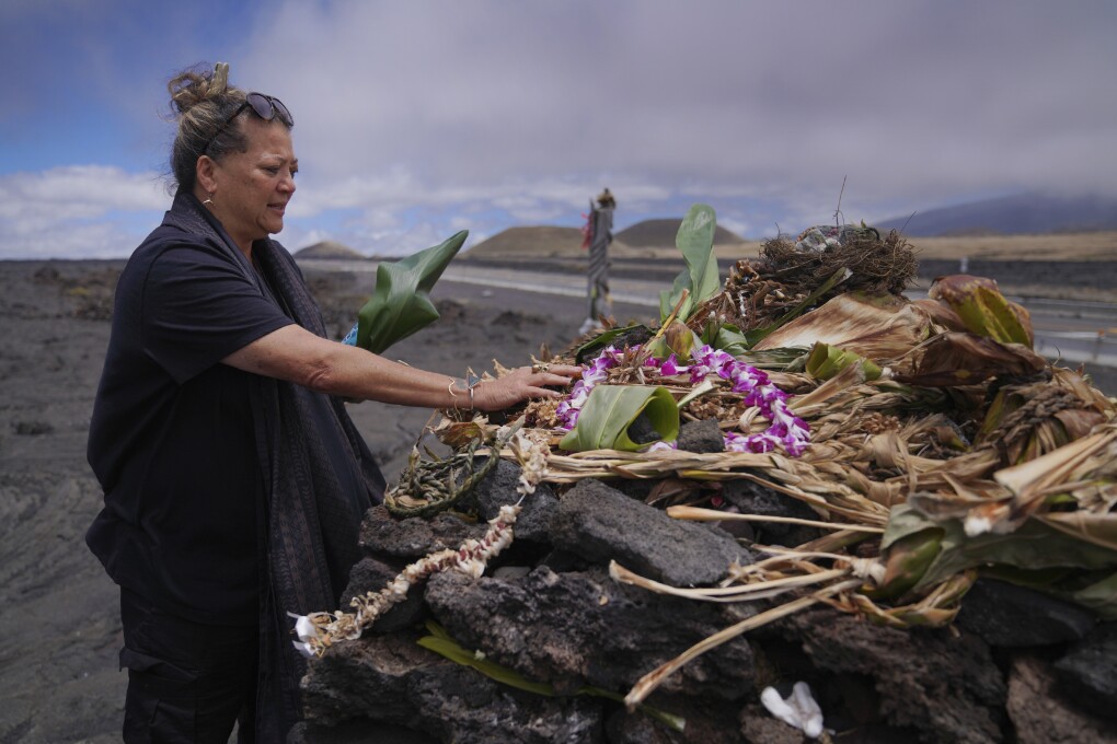 Kealoha Pisciotta, a cultural practitioner and longtime activist, lays offerings before praying at an "ahu," or ceremonial platform, part of the way up Mauna Kea in Hawaii, on Saturday, July 15, 2023. Along the slopes of this sacred mountain are ceremonial platforms, ancestral burial sites, and an alpine lake whose waters are believed to have healing properties. (AP Photo/Jessie Wardarski)